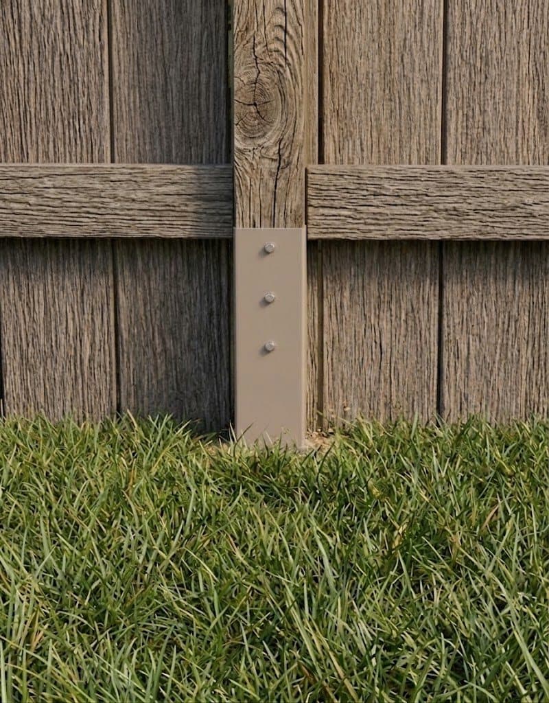 Completed fence post repair with grass restored and only the tan fixture plate visible above ground